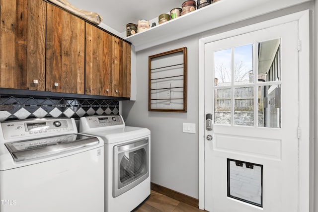 clothes washing area with washing machine and clothes dryer, cabinet space, and baseboards