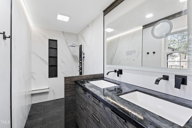 bathroom with double vanity, a marble finish shower, and a sink