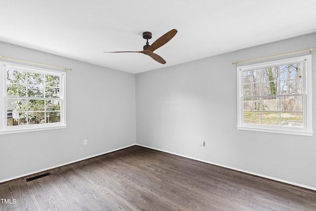 unfurnished room with plenty of natural light, visible vents, ceiling fan, and dark wood-style flooring