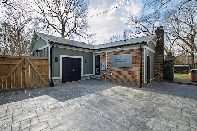 view of front of home with stone siding, a chimney, a gate, board and batten siding, and brick siding