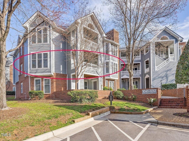 view of front of house featuring uncovered parking, crawl space, brick siding, and a front lawn