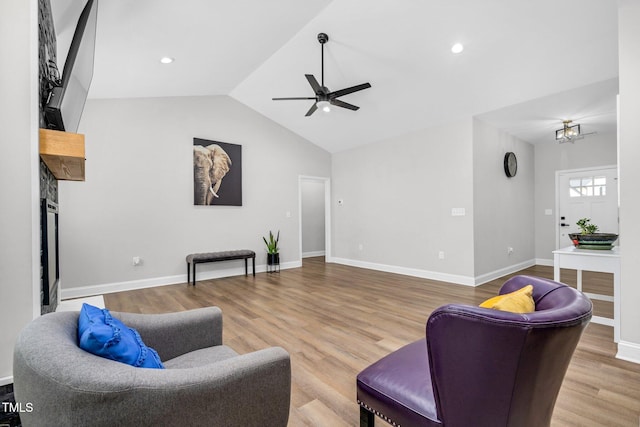 living area with lofted ceiling, ceiling fan, a fireplace, wood finished floors, and baseboards