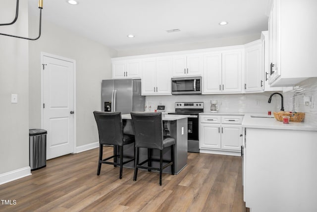 kitchen with a breakfast bar, white cabinetry, stainless steel appliances, and a sink