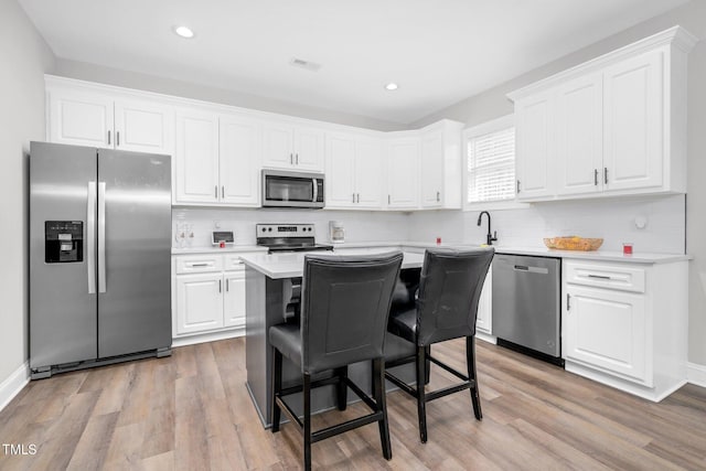 kitchen with appliances with stainless steel finishes, light countertops, and white cabinetry