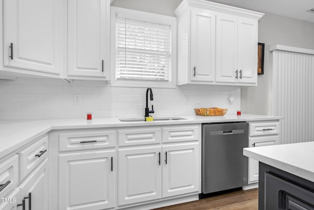 kitchen featuring tasteful backsplash, light countertops, white cabinetry, a sink, and dishwasher