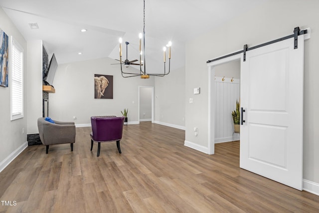 living area featuring lofted ceiling, a notable chandelier, a barn door, and wood finished floors