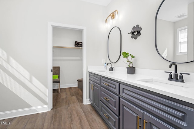 bathroom with double vanity, wood finished floors, a sink, and visible vents