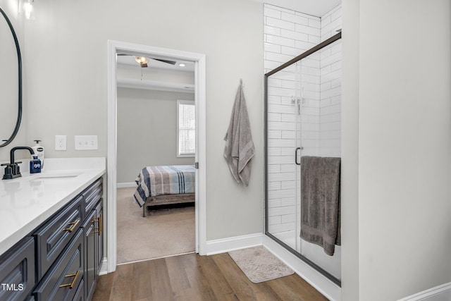 ensuite bathroom with wood finished floors, a shower stall, ensuite bath, vanity, and baseboards