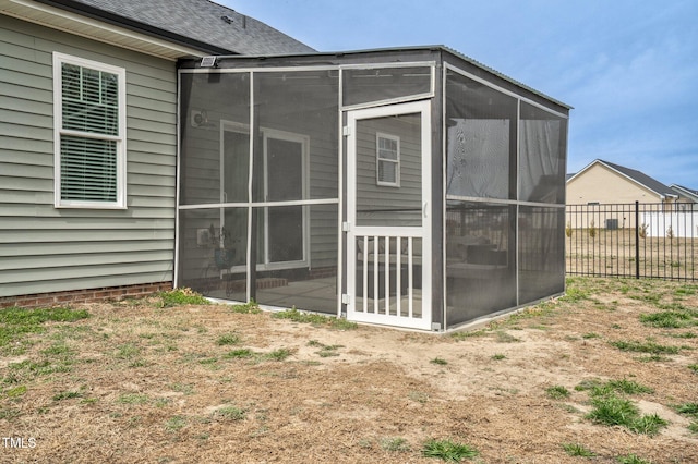 view of outdoor structure with fence and a sunroom