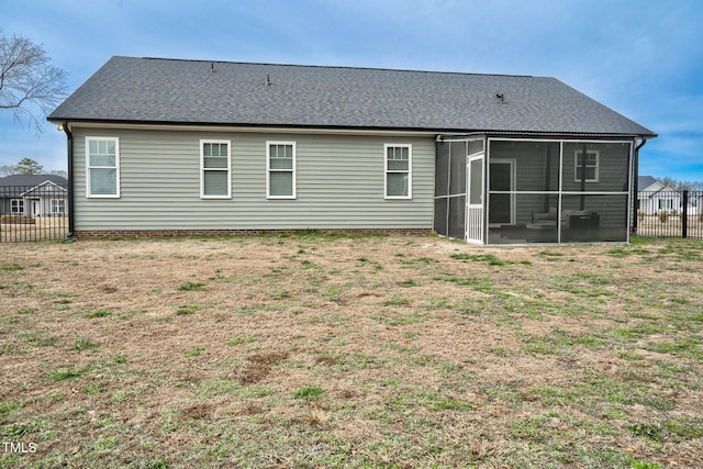 rear view of property featuring roof with shingles, a lawn, fence, and a sunroom