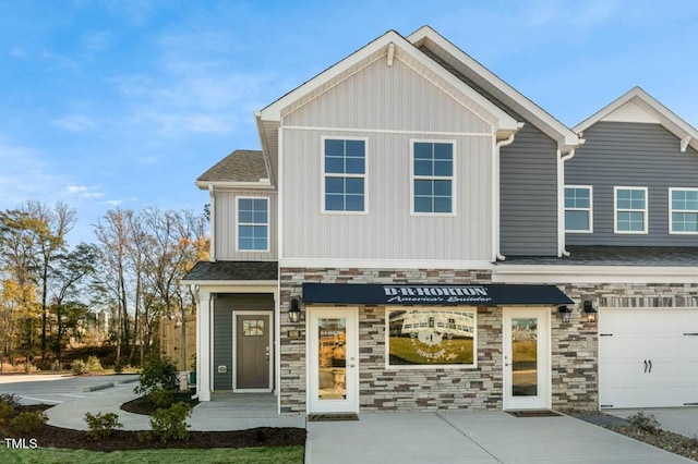 view of front facade with stone siding, board and batten siding, and concrete driveway