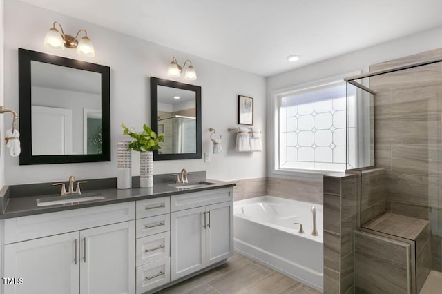 bathroom with a stall shower, a sink, a bath, and double vanity