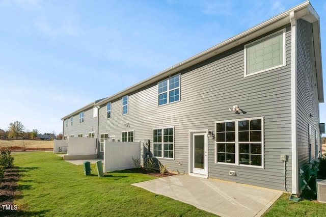 rear view of property featuring a patio, a yard, central AC, and fence