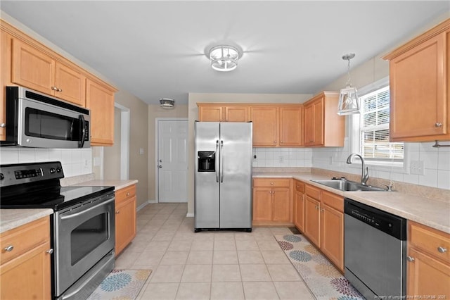 kitchen with light tile patterned floors, appliances with stainless steel finishes, a sink, and light brown cabinetry