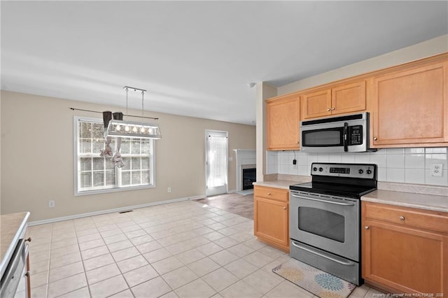 kitchen with light tile patterned floors, stainless steel appliances, backsplash, and light countertops