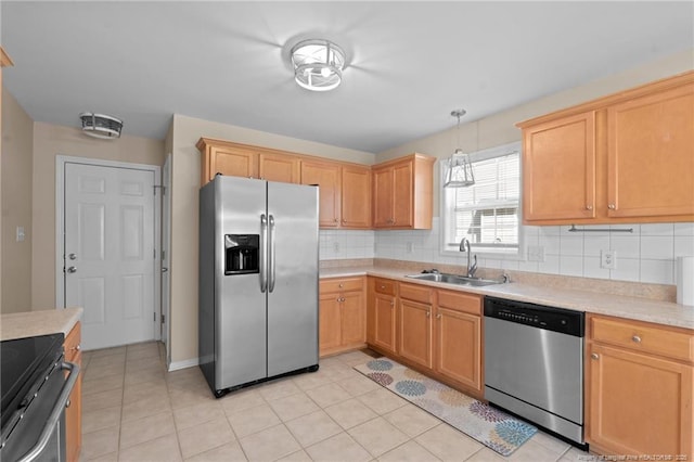 kitchen featuring decorative light fixtures, stainless steel appliances, light countertops, decorative backsplash, and a sink