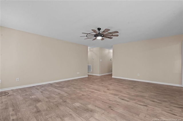 spare room with light wood-style floors, ceiling fan, visible vents, and baseboards