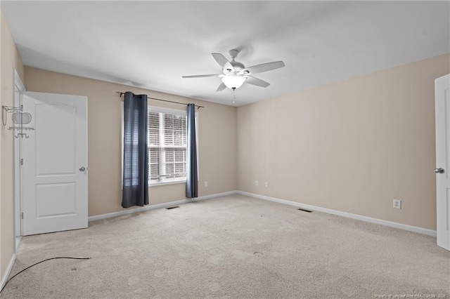 carpeted spare room with a ceiling fan, visible vents, and baseboards