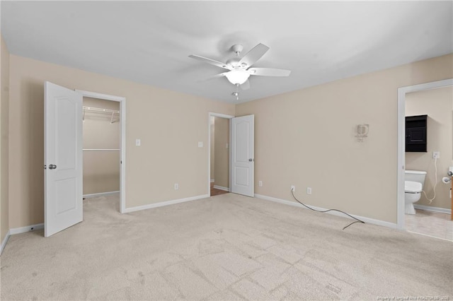 unfurnished bedroom with light carpet, baseboards, a walk in closet, and a closet