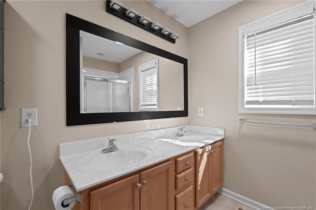 bathroom featuring baseboards, double vanity, a sink, and a shower stall