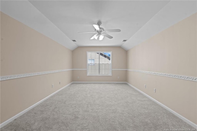 carpeted empty room featuring vaulted ceiling, ceiling fan, visible vents, and baseboards