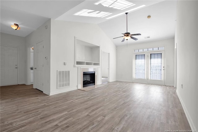 unfurnished living room with lofted ceiling, visible vents, a fireplace, and wood finished floors