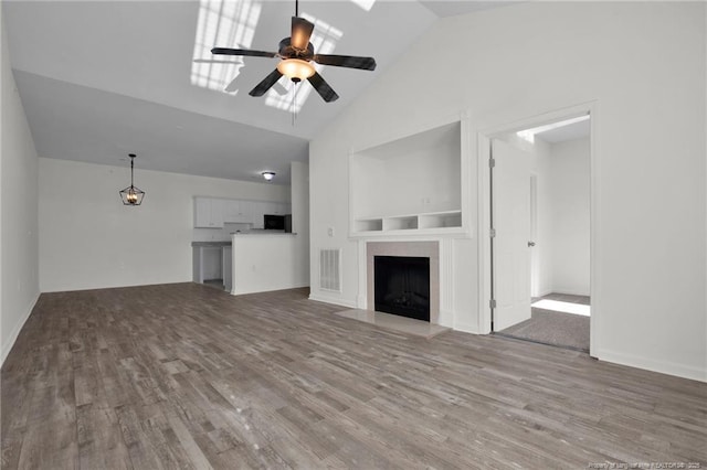 unfurnished living room featuring visible vents, a fireplace, a ceiling fan, and wood finished floors