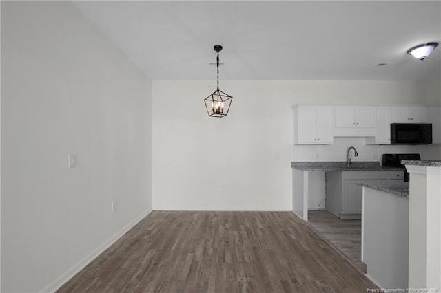 interior space with decorative backsplash, white cabinets, a sink, wood finished floors, and black microwave