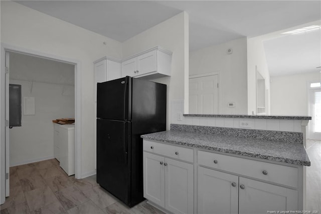 kitchen with washer / dryer, light stone counters, freestanding refrigerator, a peninsula, and white cabinetry