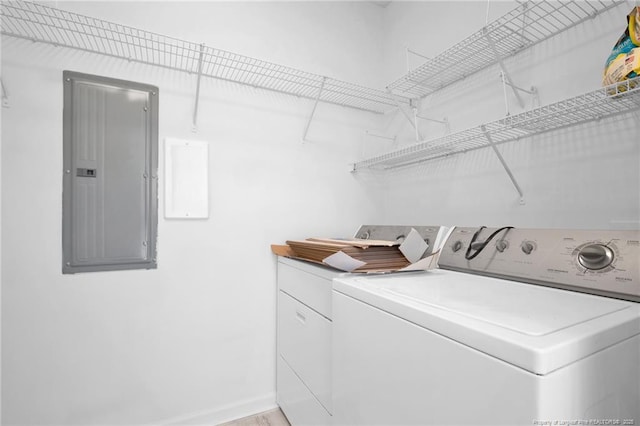 clothes washing area featuring laundry area, electric panel, baseboards, and washer and dryer