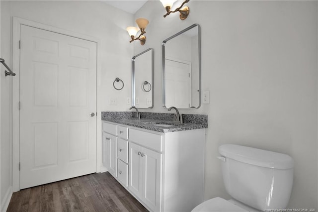 full bathroom with double vanity, a sink, toilet, and wood finished floors