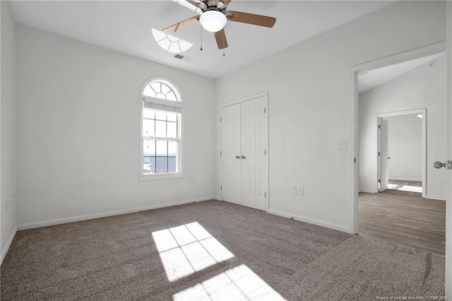 unfurnished bedroom with baseboards, visible vents, vaulted ceiling, carpet flooring, and a closet