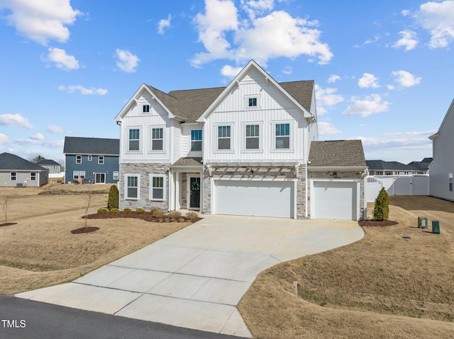 view of front of property featuring a garage, fence, driveway, stone siding, and board and batten siding