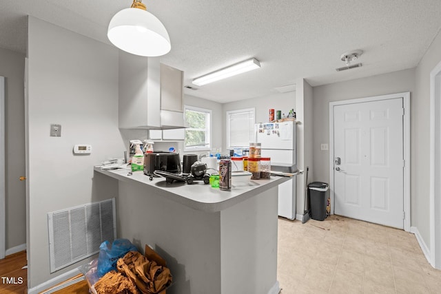 kitchen featuring a peninsula, light countertops, visible vents, and white cabinetry