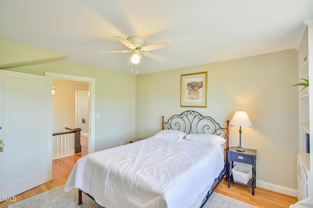 bedroom featuring light wood finished floors, baseboards, and a ceiling fan