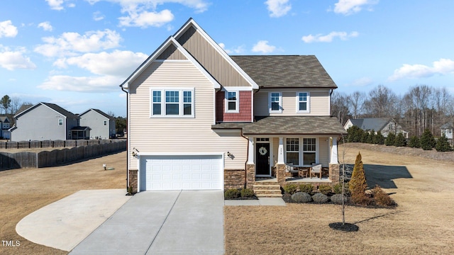 craftsman-style house featuring covered porch, concrete driveway, an attached garage, board and batten siding, and stone siding