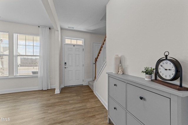 entrance foyer with light wood-type flooring, visible vents, baseboards, and stairs