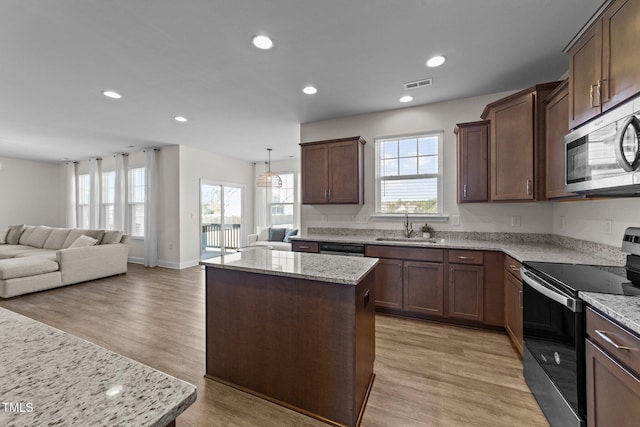 kitchen featuring visible vents, light wood-style flooring, a kitchen island, stainless steel appliances, and a sink