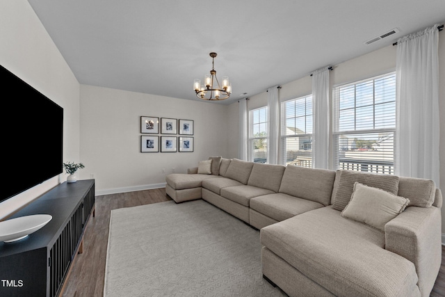 living area featuring baseboards, dark wood finished floors, visible vents, and a notable chandelier