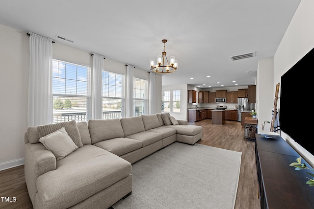 living area with recessed lighting, visible vents, light wood-style floors, a chandelier, and baseboards