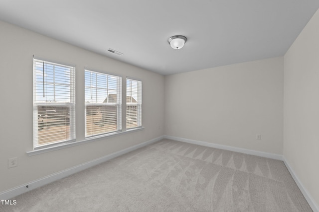 empty room with baseboards, visible vents, and light colored carpet