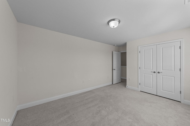 unfurnished bedroom with baseboards, a closet, and light colored carpet