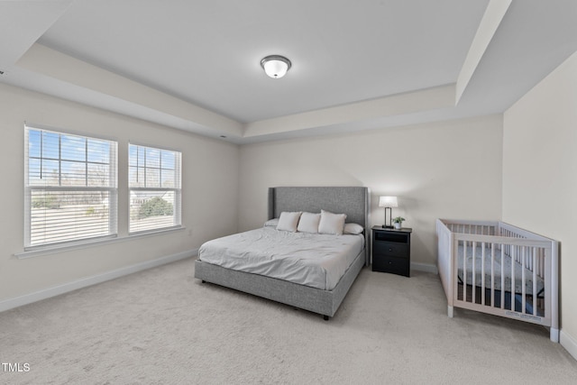 carpeted bedroom featuring baseboards and a tray ceiling