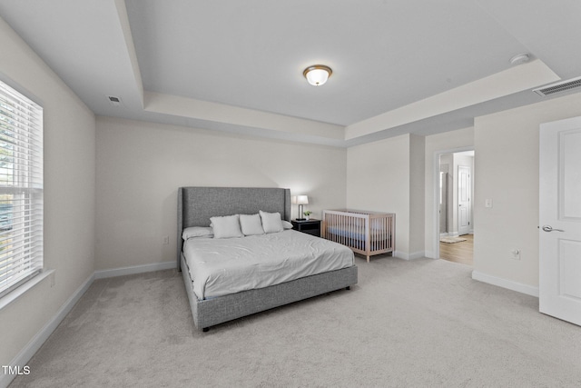 bedroom featuring carpet floors, a tray ceiling, visible vents, and baseboards