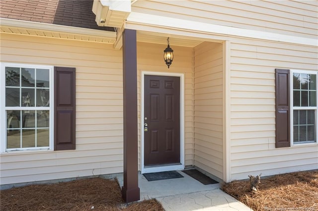 view of exterior entry featuring a shingled roof