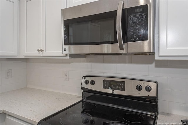 kitchen with light stone countertops, tasteful backsplash, white cabinetry, and stainless steel appliances