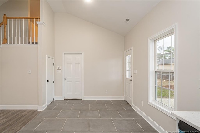 foyer with high vaulted ceiling, visible vents, and baseboards