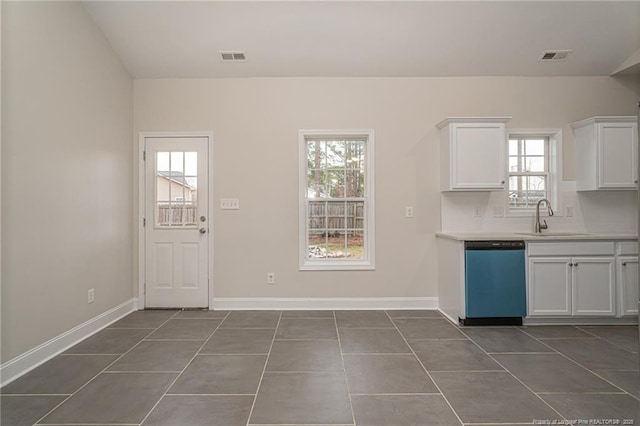 kitchen featuring light countertops, white cabinets, a sink, dark tile patterned flooring, and dishwasher