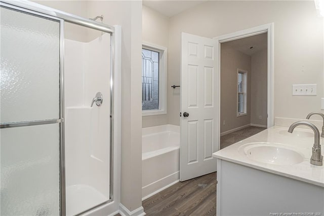 bathroom with a bath, a stall shower, a sink, and wood finished floors