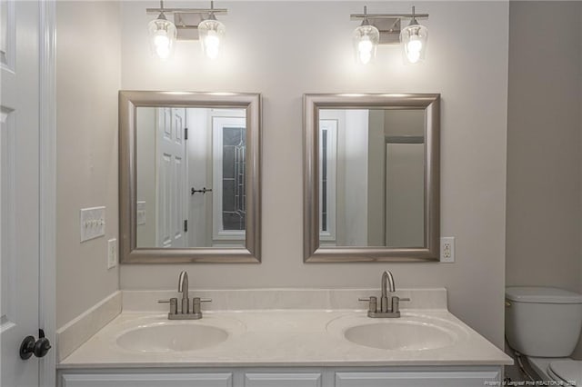 full bathroom with double vanity, a sink, and toilet